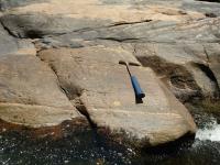 Textura migmatítica com megacristal de feldspato (plagioclásio) rotacionado. Martelo orientado para Norte.