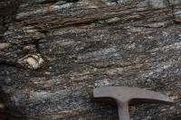 Megacristal de feldspatop (plagioclásio) em feldspato biotita gnaisse. Martelo orientado para Norte.